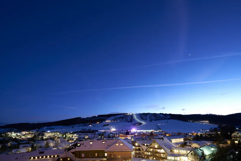 Willingen am Winterabend mit beleuchteten Häusern und Flutlicht am Hang